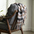 white brown and black plaid designed throw blanket draped across a sofa