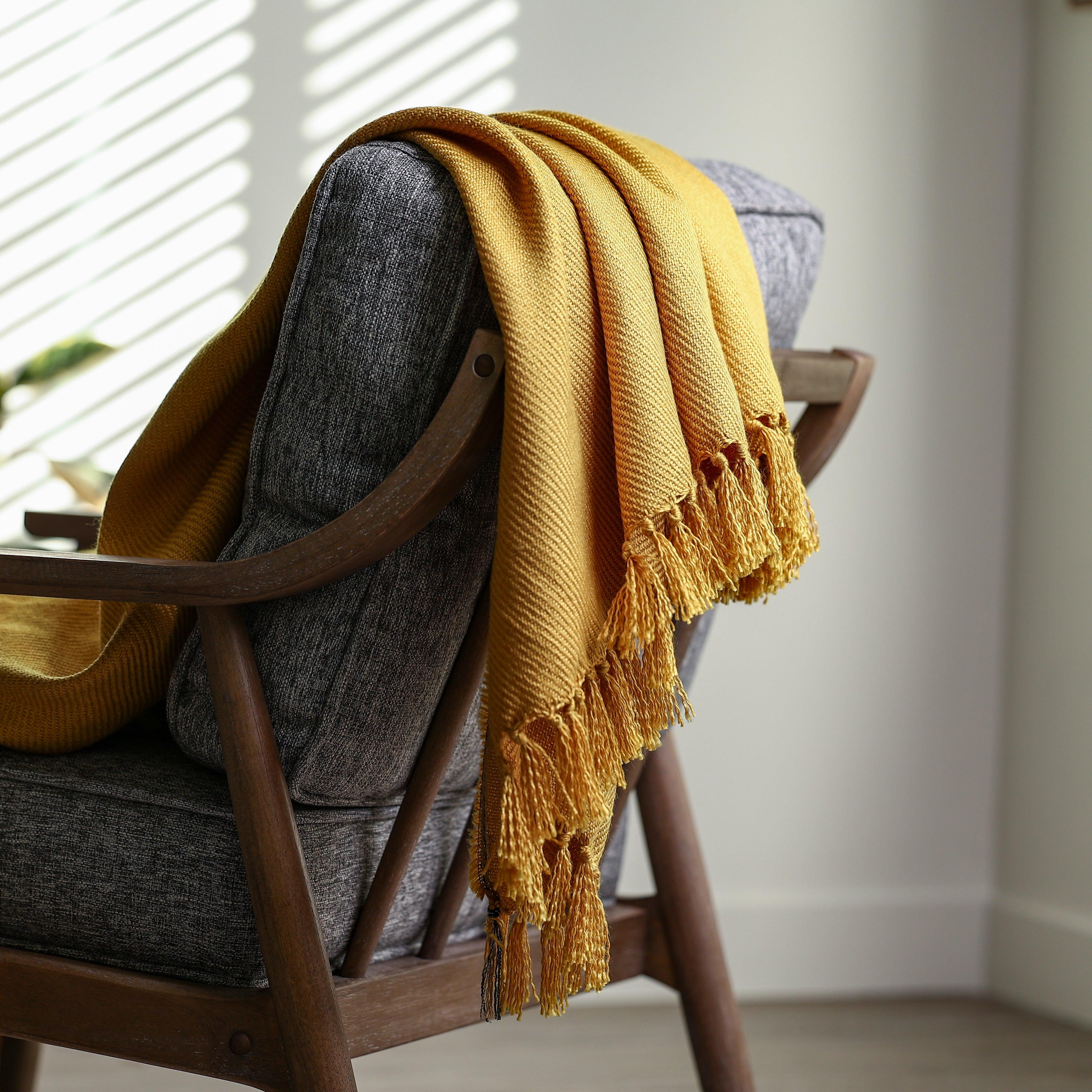 soft yellow acrylic throw blanket draped and styled over a couch decoratively