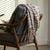 brown cream and black plaid throw blanket styled over a chair with tassels