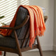 orange textured cotton blend throw blanket styled over a chair