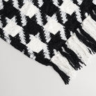 white and black houndstooth patterned throw blanket styled to show the tassels and pattern of the designer blanket