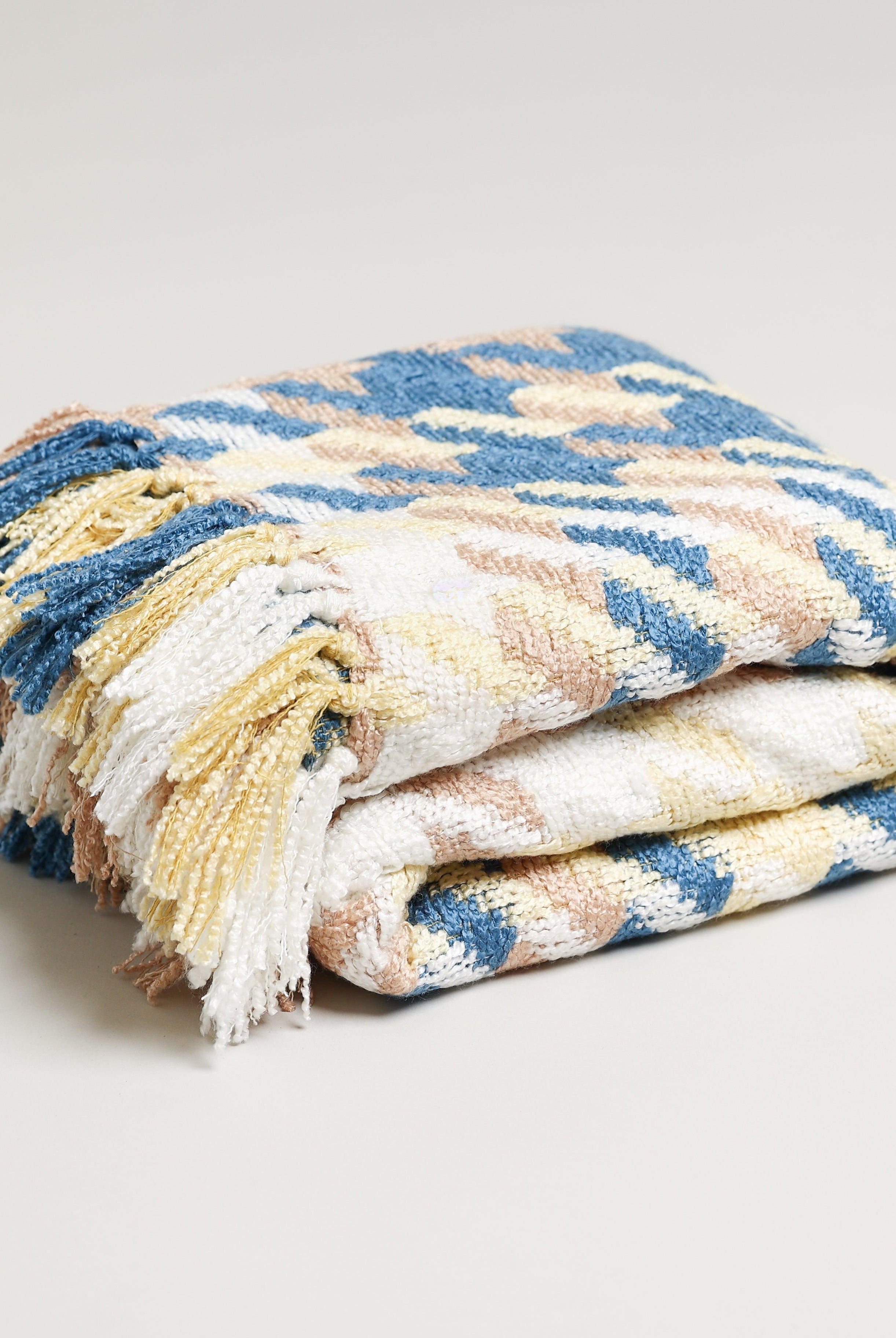 yellow white and blue folded throw blanket with tassels made from acrylic