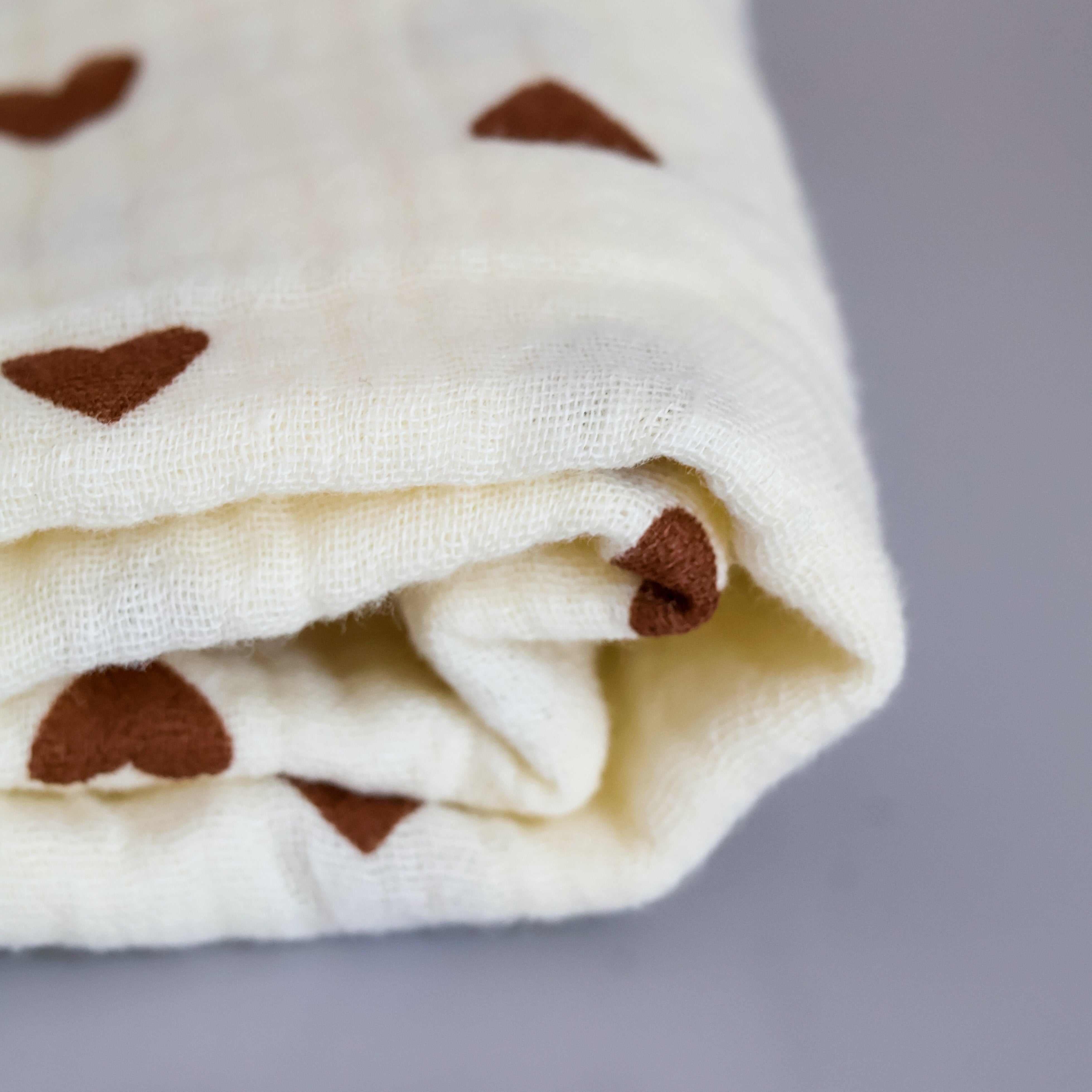 corner of folded brown hearted swaddle blanket