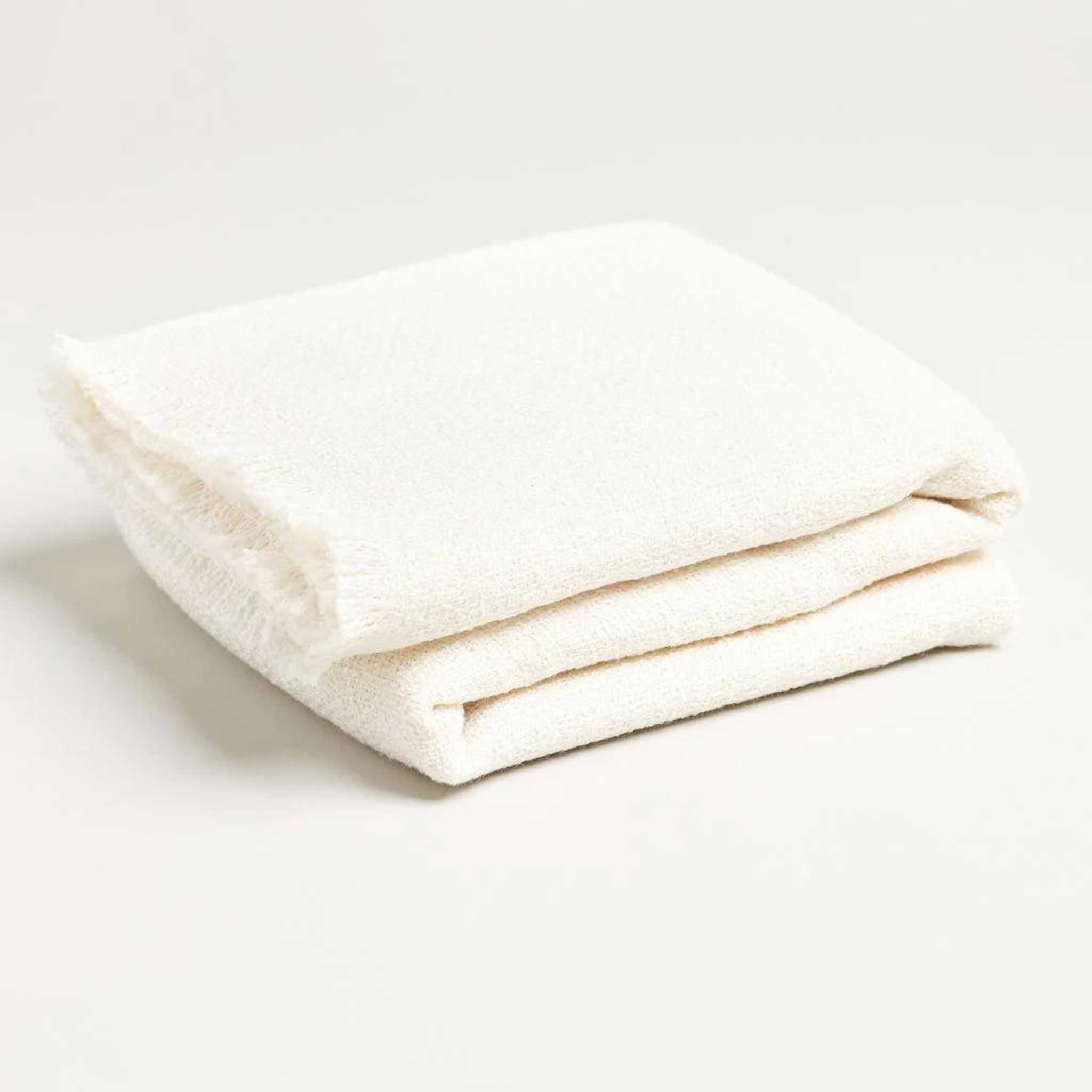 cream and white colored throw blanket folded up with a fringe perfect for styling and decor