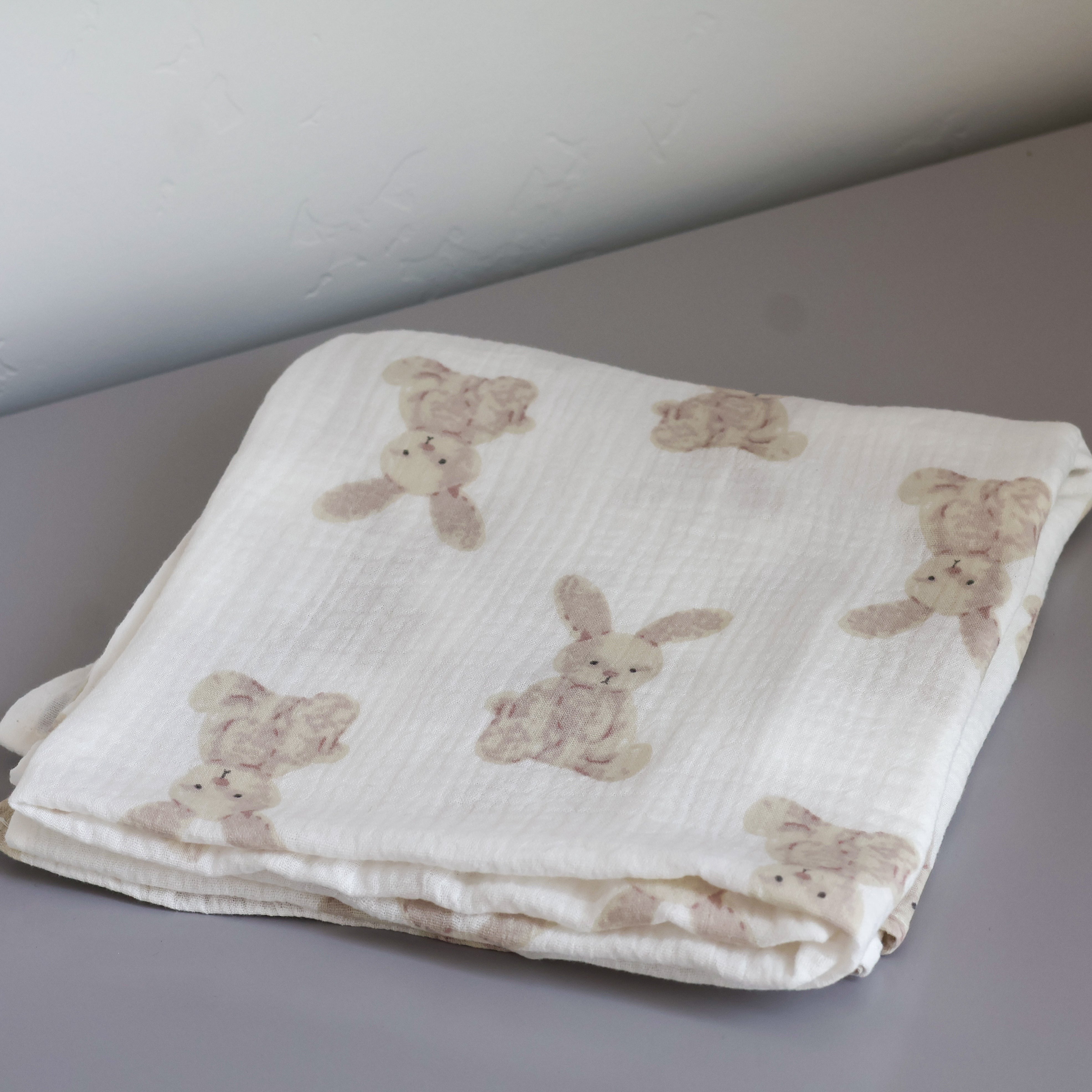 a image of a folded bunny pattern baby blanket on a dresser by boucle