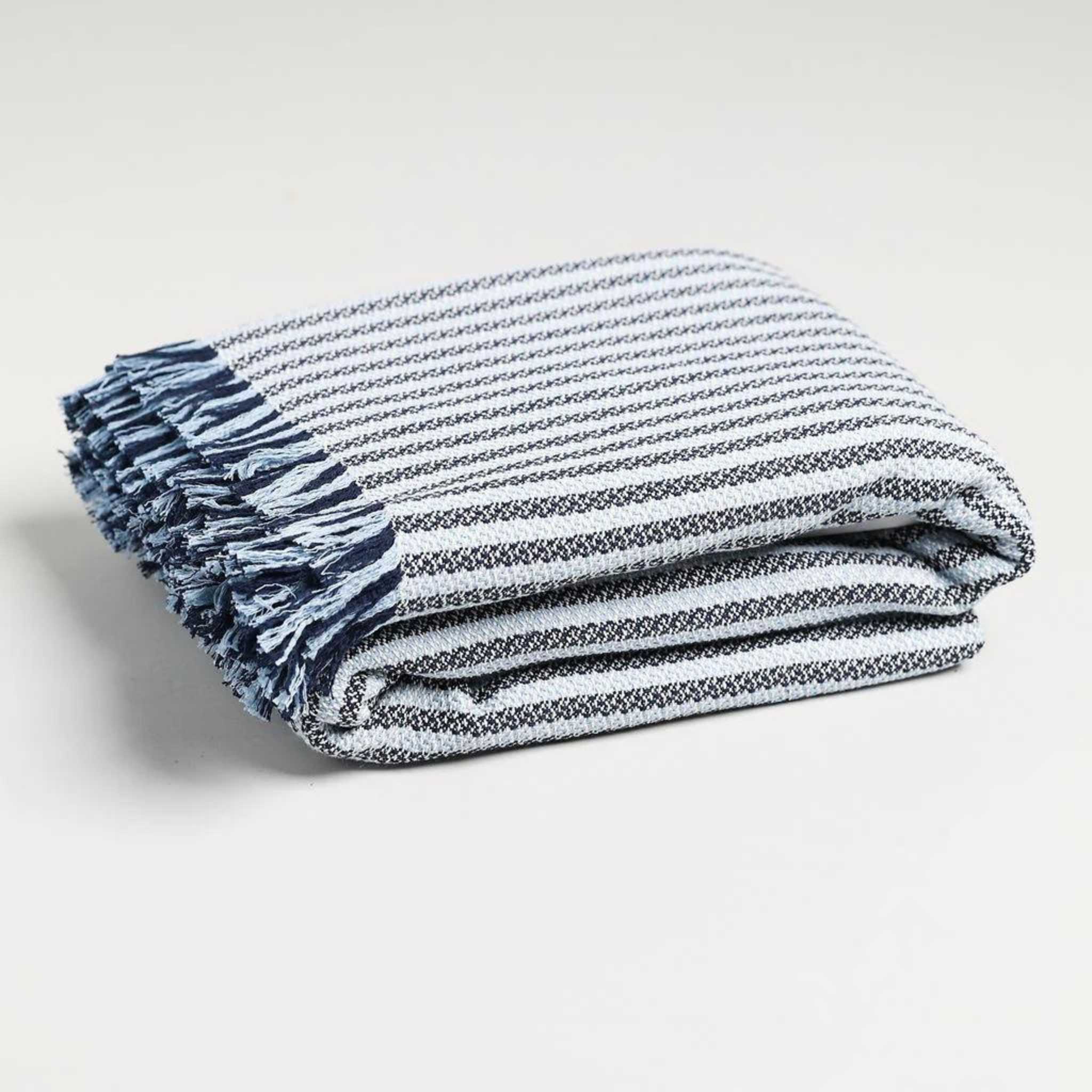 a image of our navy blue striped throw blanket folded up with a fringe