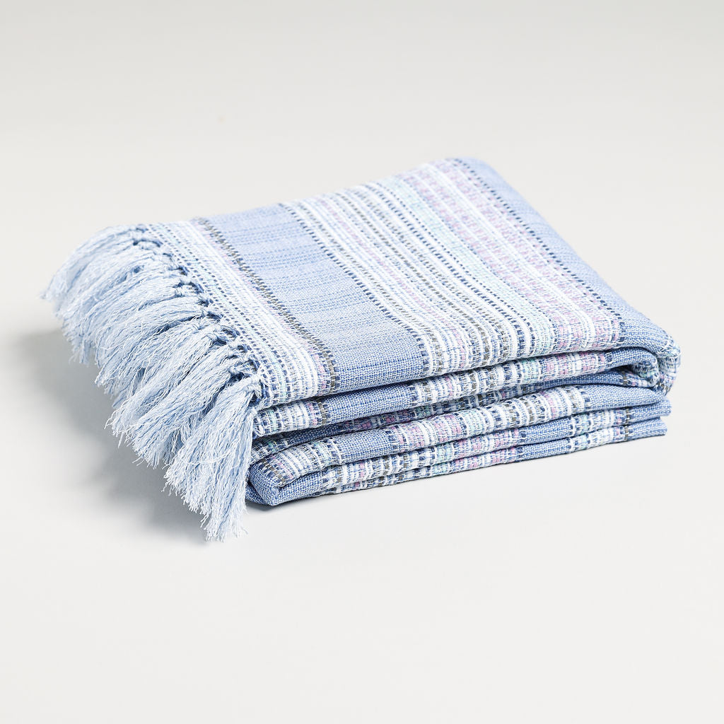 A picture of a lavender throw blanket folded nicely with stripes and a blue pattern