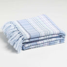 A picture of a lavender throw blanket folded nicely with stripes and a blue pattern