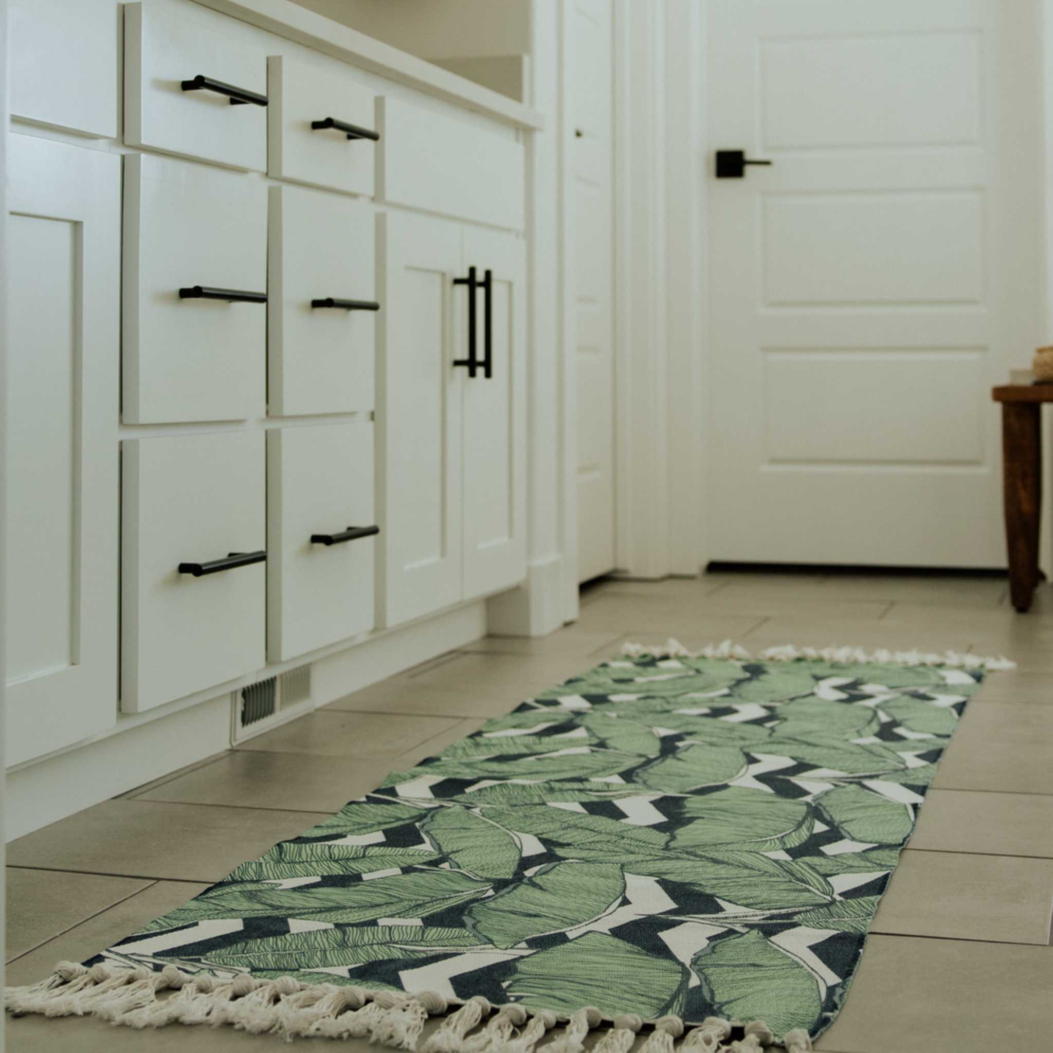 leaf patterned rug styled in a bathroom with tassels and a cool green leaf design on it