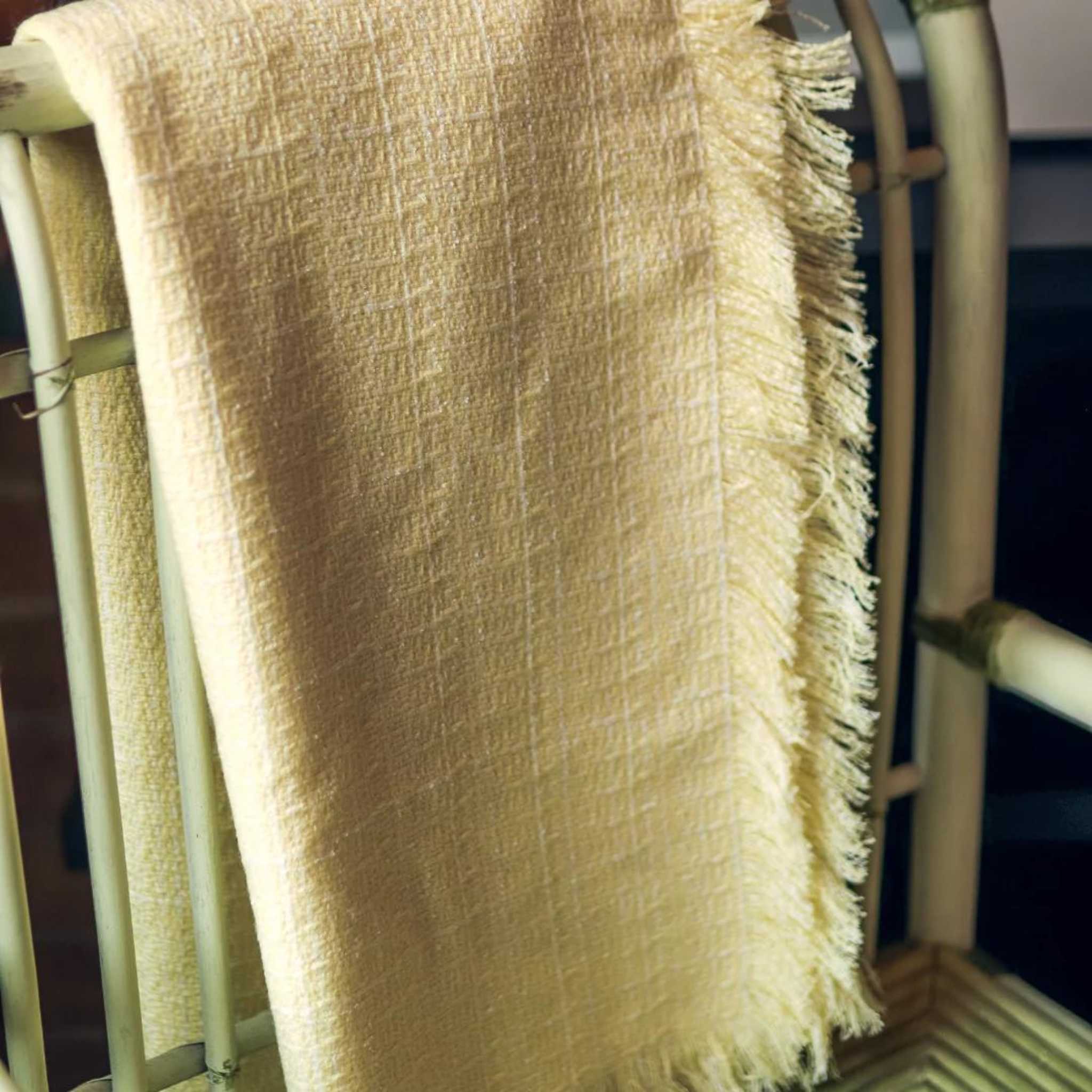 detailed view of pale yellow throw blanket draped and styled over a sofa chair